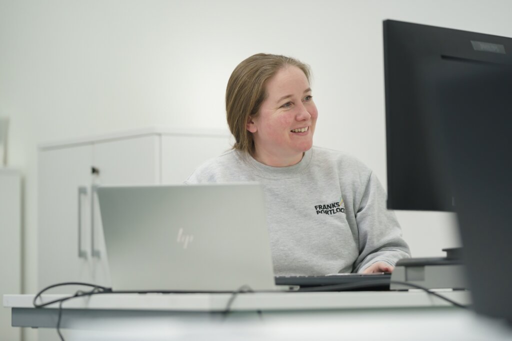 A photo of Sara Johnson, Financial Controller, at her desk, smiling at her screen.